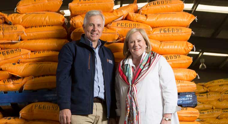 rob and ann damin standing in front of a pile of seed sacks